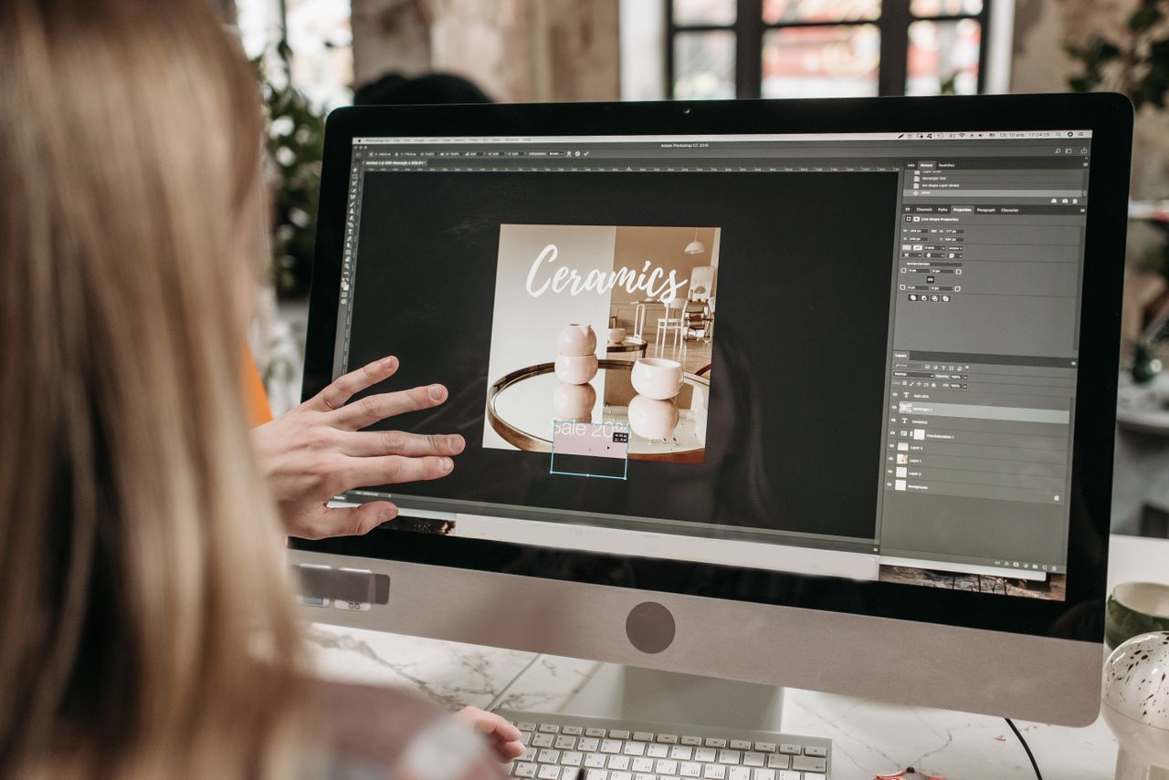 A graphic designer works on a ceramics promotion using Adobe Photoshop on an iMac.
